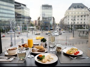 A table with breakfast items and drinks, overlooking a city street with buildings and vehicles. - Mercure Budapest Korona Hotel (Budapest)
