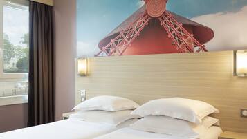 Relax in a spacious room with a large bed and wall-mounted light fixture, featuring a comfortable headboard and a large window with a view.