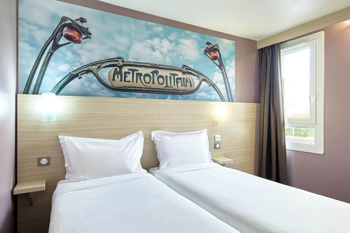 A hotel room with a bed, a nightstand, and a wall with a 'METROPOLITANIA' sign.
