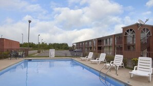 A swimming pool with lounge chairs and a brick building with balconies. - Days Inn by Wyndham Jonesboro AR (Jonesboro)