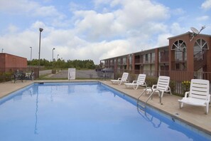 Una piscina al aire libre, sillones reclinables de piscina