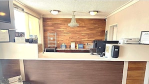 A reception area with a wooden wall, a chandelier, a computer, and a coffee machine. - Days Inn by Wyndham Jonesboro AR (Jonesboro)