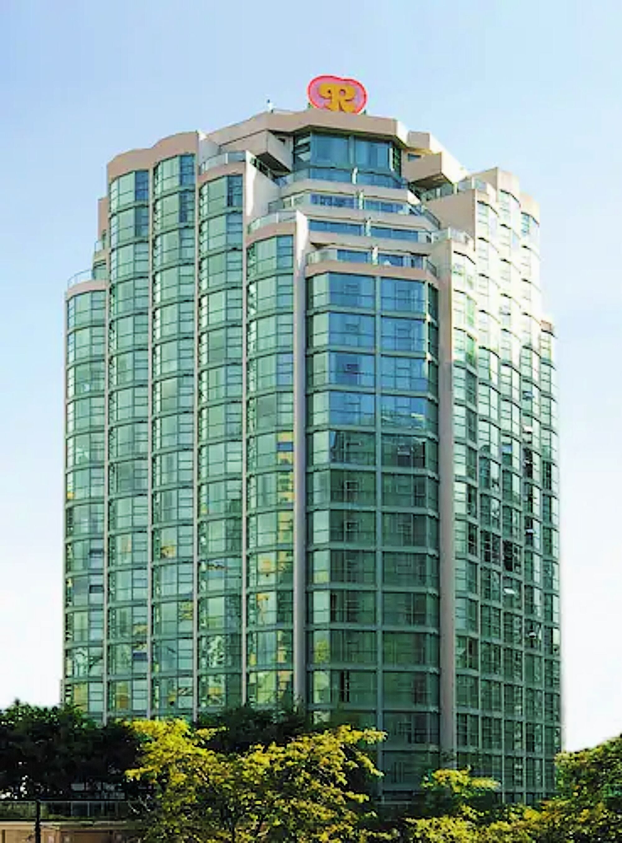 A tall, modern building with a distinctive logo at the top.