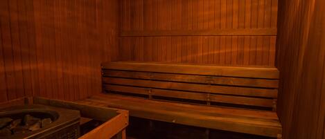 A sauna with wooden benches and a stone basin.