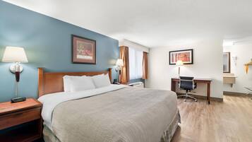Una habitación de hotel con cama, mesitas de noche, escritorio y una silla.