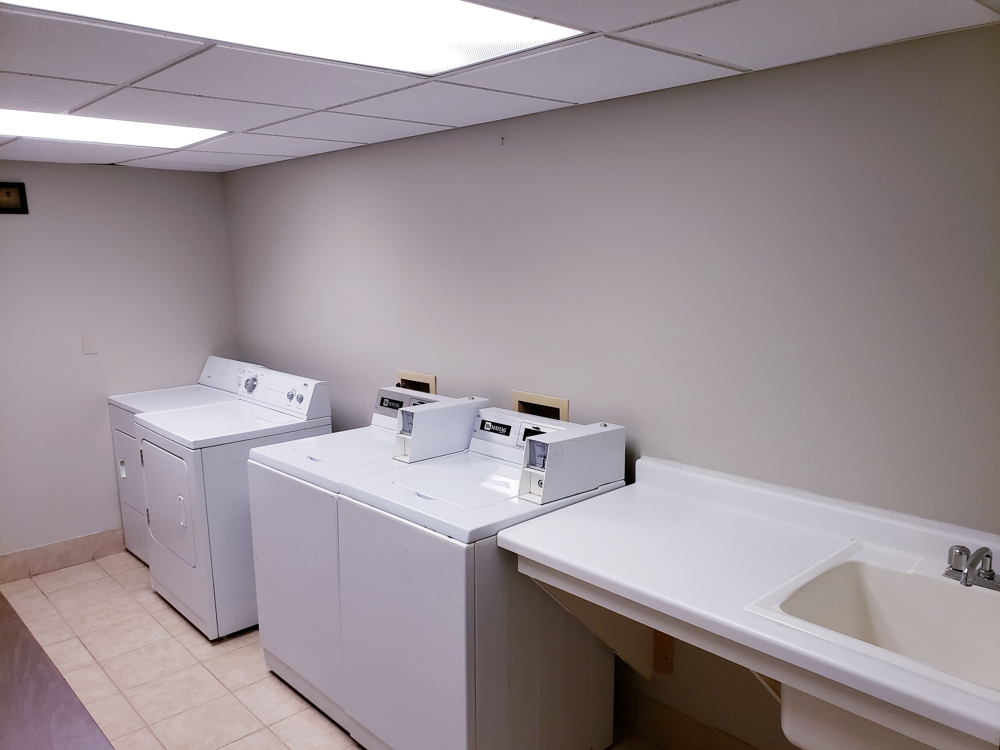 Una sala de lavandería con dos lavadoras y un lavabo.