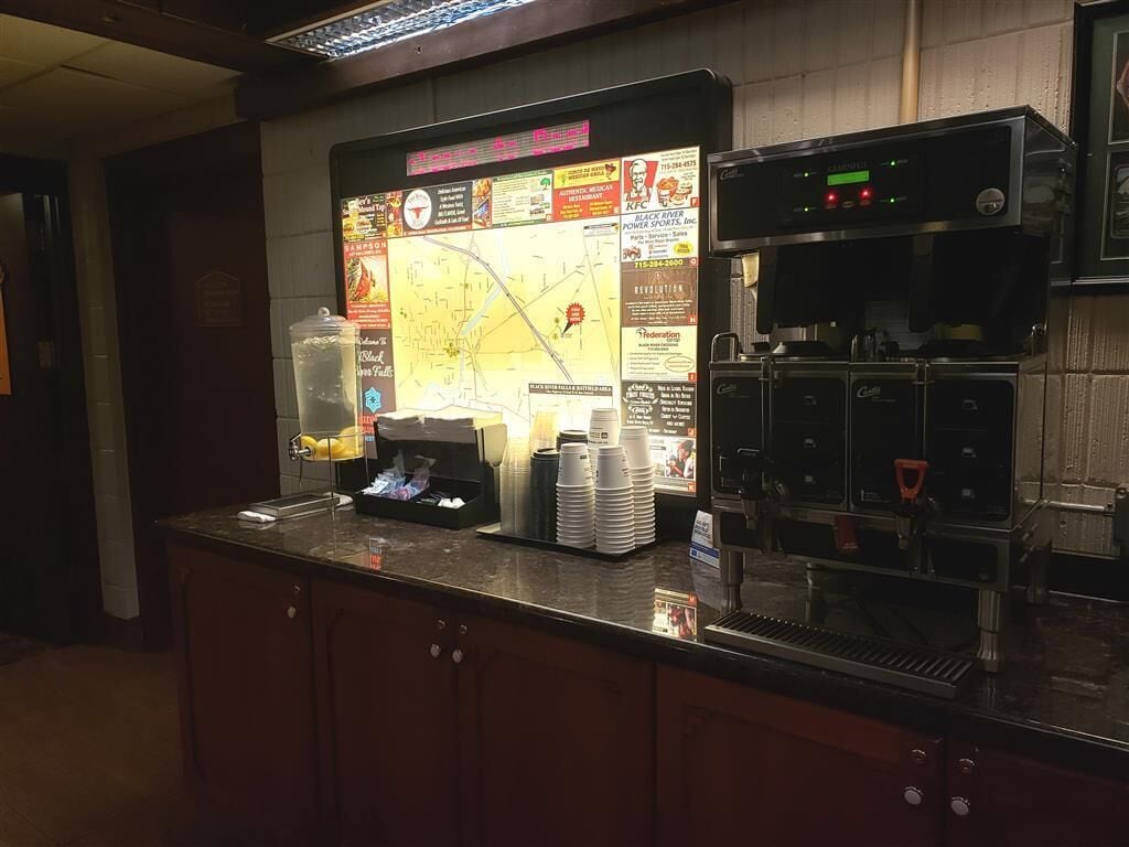Una estación de café con un mapa y varios anuncios, incluyendo KFC y una máquina de café.