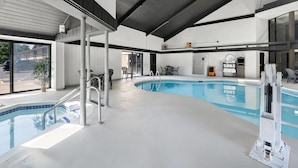 Une piscine intérieure offrant une vue dégagée sur l’espace piscine, un coin salon et une porte donnant sur l’extérieur.