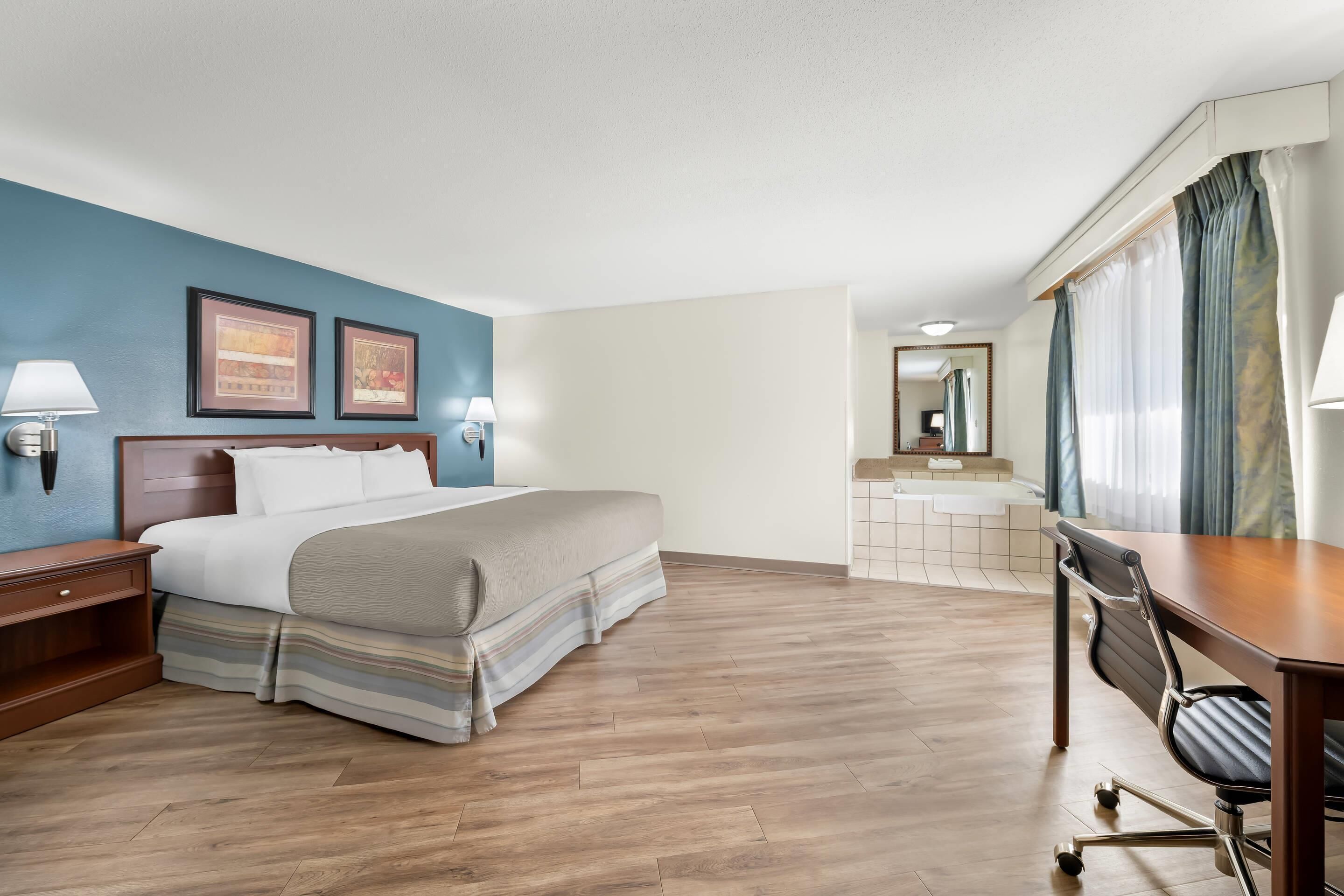 A hotel room with a bed, desk, chair, and bathroom.