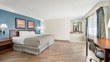 A hotel room with a bed, desk, chair, and bathroom.