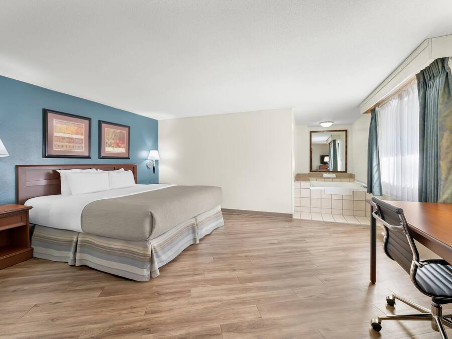 A hotel room with a bed, desk, chair, and bathroom.