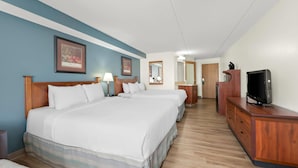 Une chambre d’hôtel avec un grand lit, une télévision, une commode et un miroir.