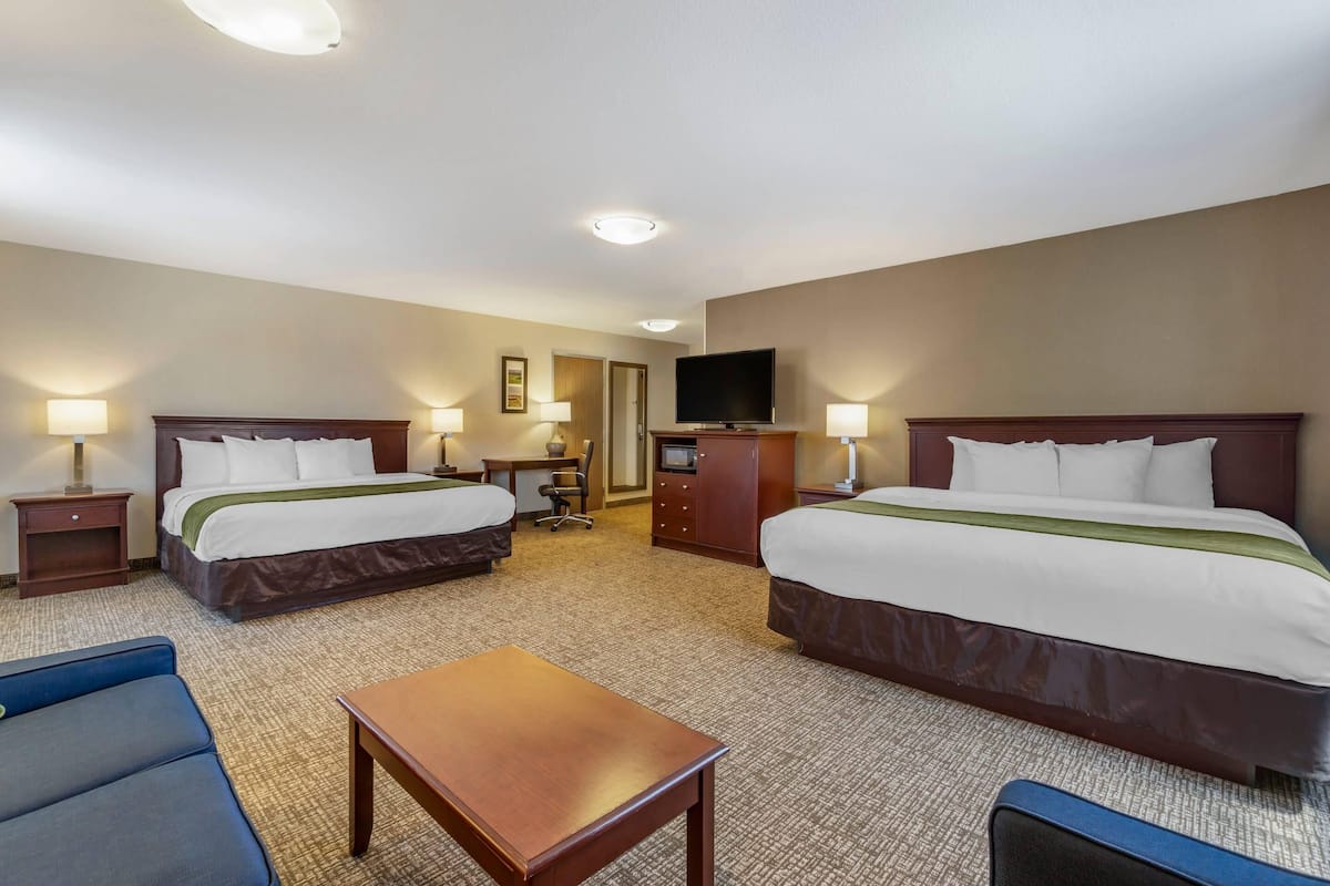 A hotel room with two beds, a TV, a desk, and a chair.