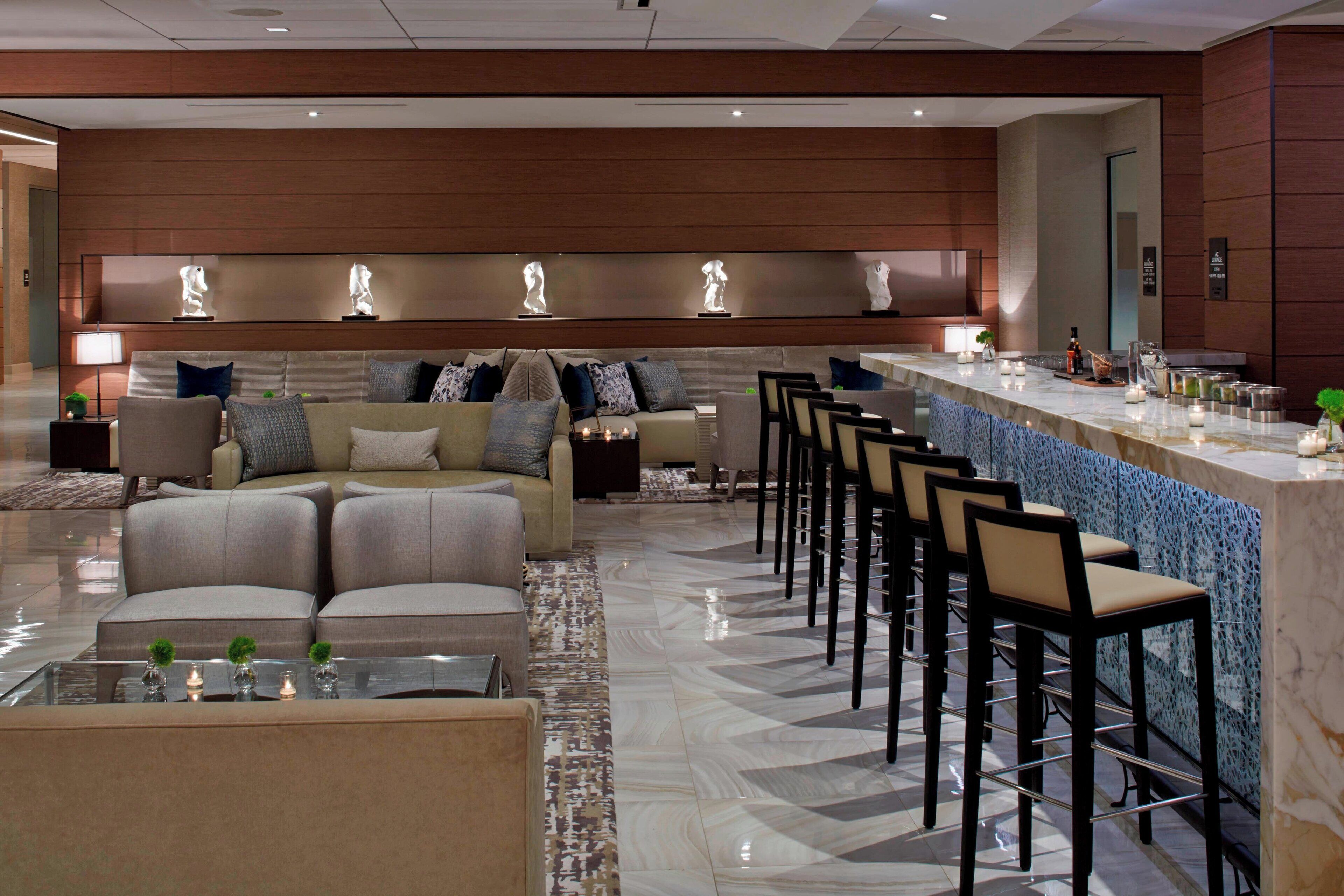 Een moderne hotellobby met een zithoek, een bar en een receptiebalie.
