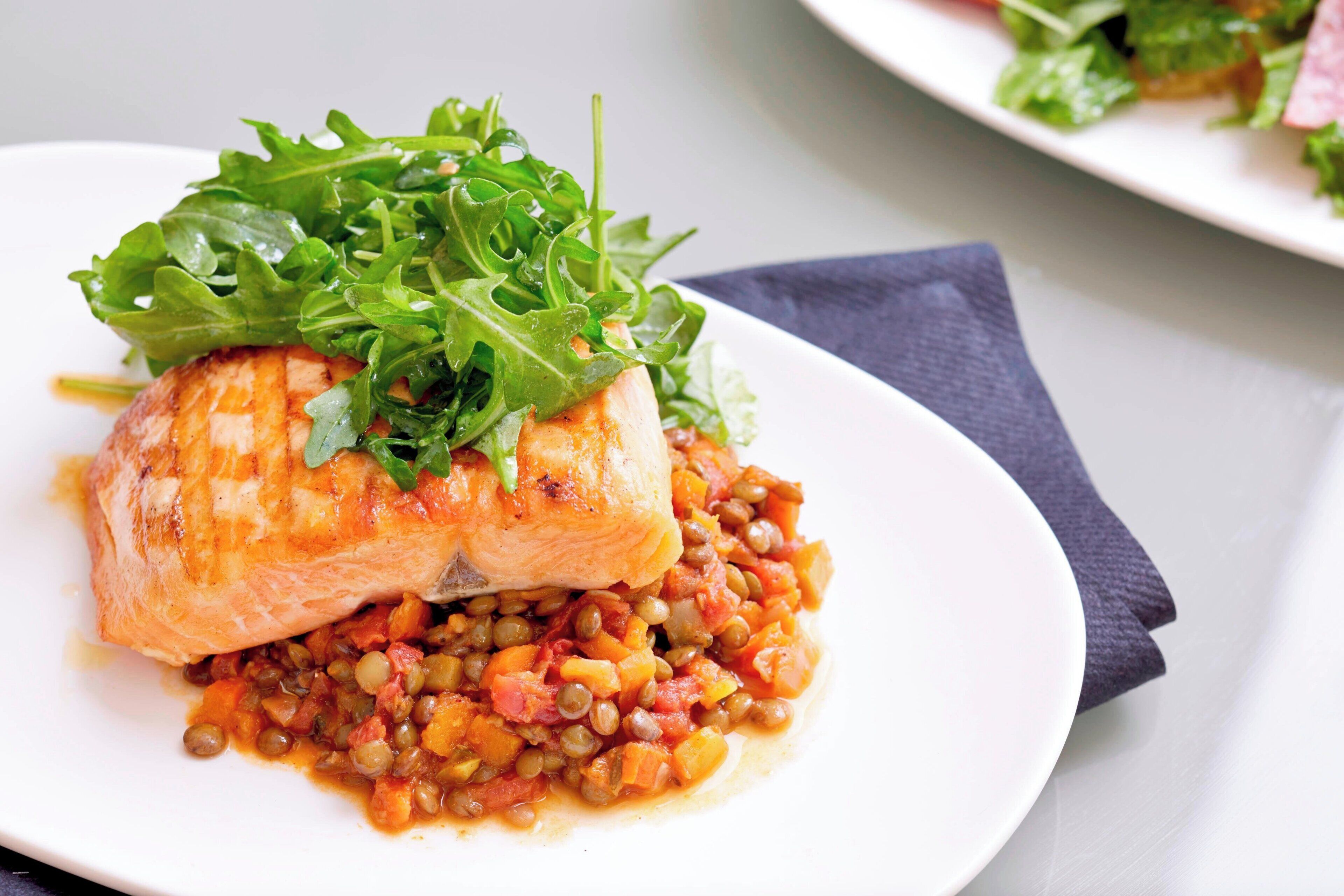 A plate of food with a piece of fish and lentils.