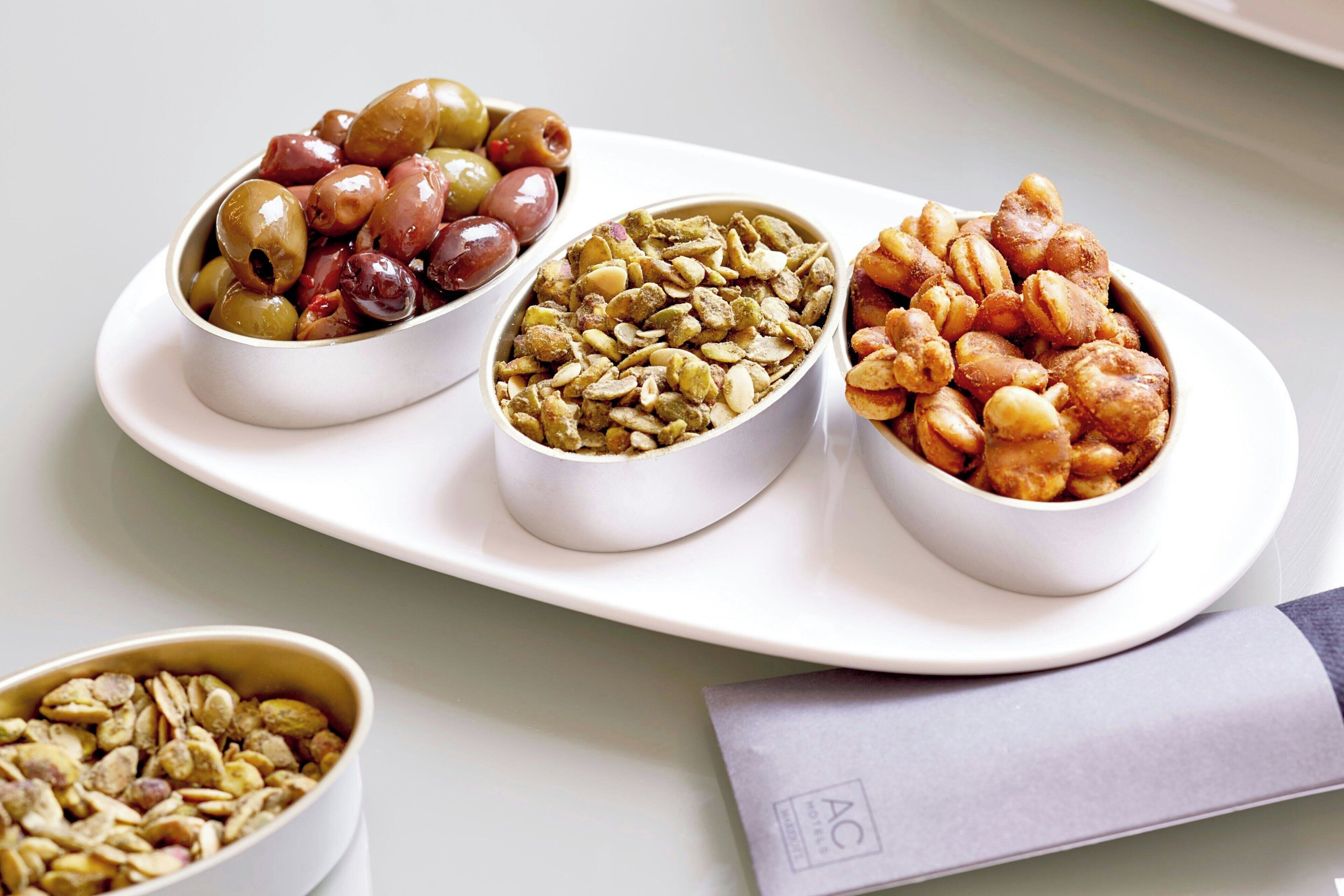 Trois bols contenant différents types d’en-cas, présentés sur une assiette blanche.
