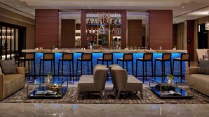 A bar area with a counter, multiple bar stools, and a seating area with two sofas and a coffee table. - AC Hotel by Marriott Atlanta Downtown (Atlanta)