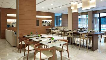 A modern dining area with multiple tables and chairs, a sofa, and a pool view.