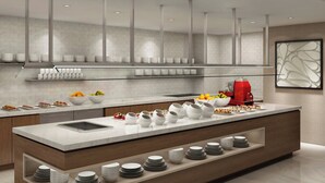 A modern kitchen with a central island, white marble countertops, and a variety of dishes and fruits. - AC Hotel by Marriott Atlanta Downtown (Atlanta)