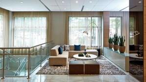 A spacious lobby with a modern sofa set, a coffee table, and a staircase with glass railings. - AC Hotel by Marriott Atlanta Downtown (Atlanta)