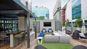An outdoor patio with a dining area, seating, and a TV screen. - AC Hotel by Marriott Atlanta Downtown (Atlanta)