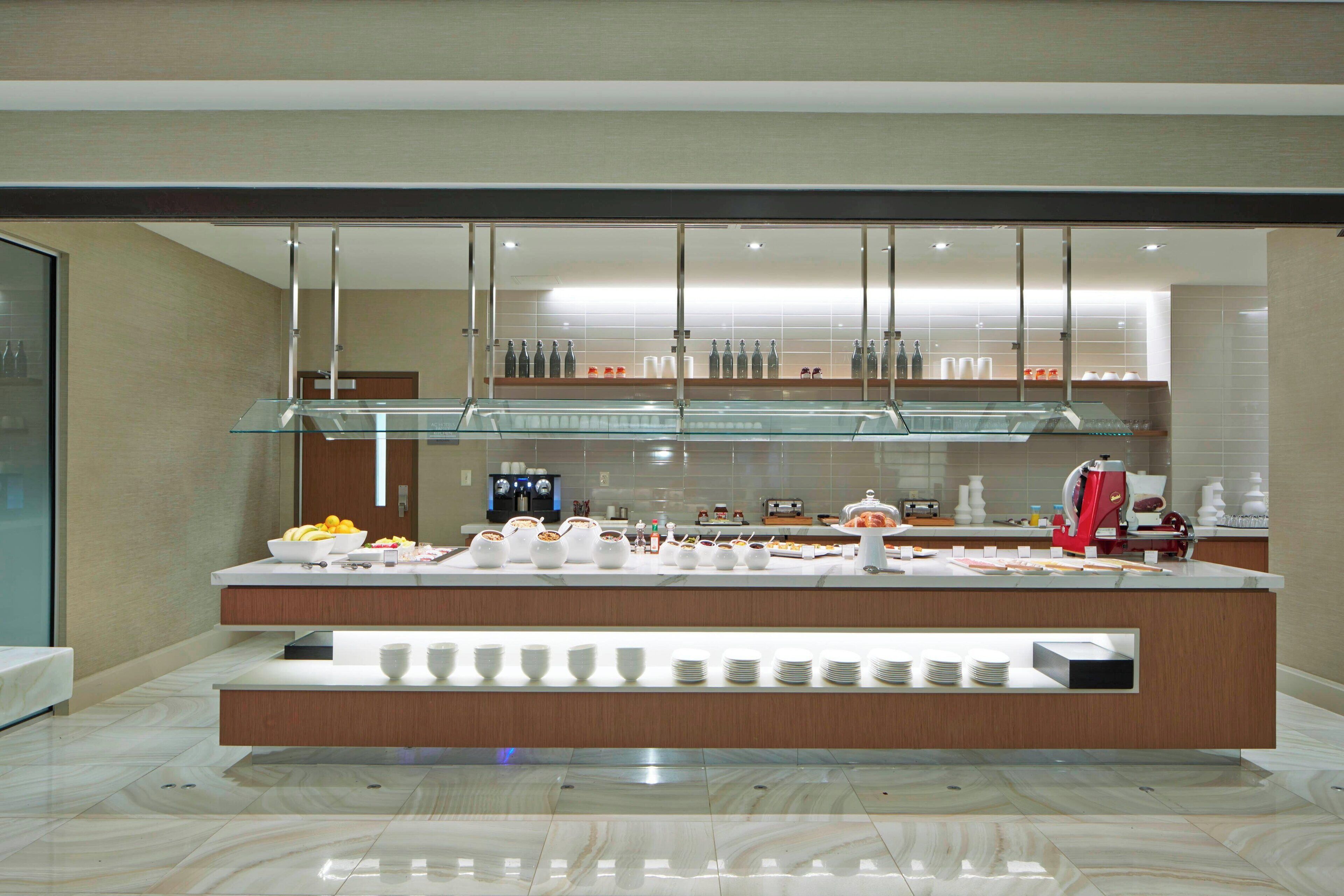 A modern breakfast bar with glass display cases, a coffee machine, and neatly arranged dishes.
