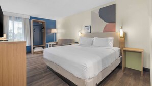 Una camera d'albergo con un letto grande, una scrivania, una sedia, un armadio e uno spazio doccia.
