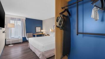Habitación de hotel con cama, mesita de noche, lámpara y un tendedero de pared.