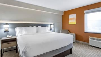 A hotel room with a large bed, bedside tables, a desk, and a window.