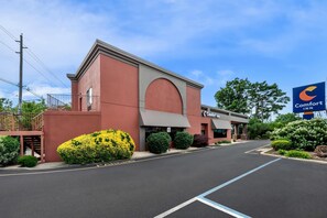 A Comfort Inn hotel with a red facade, a large arched entrance, and a parking lot.