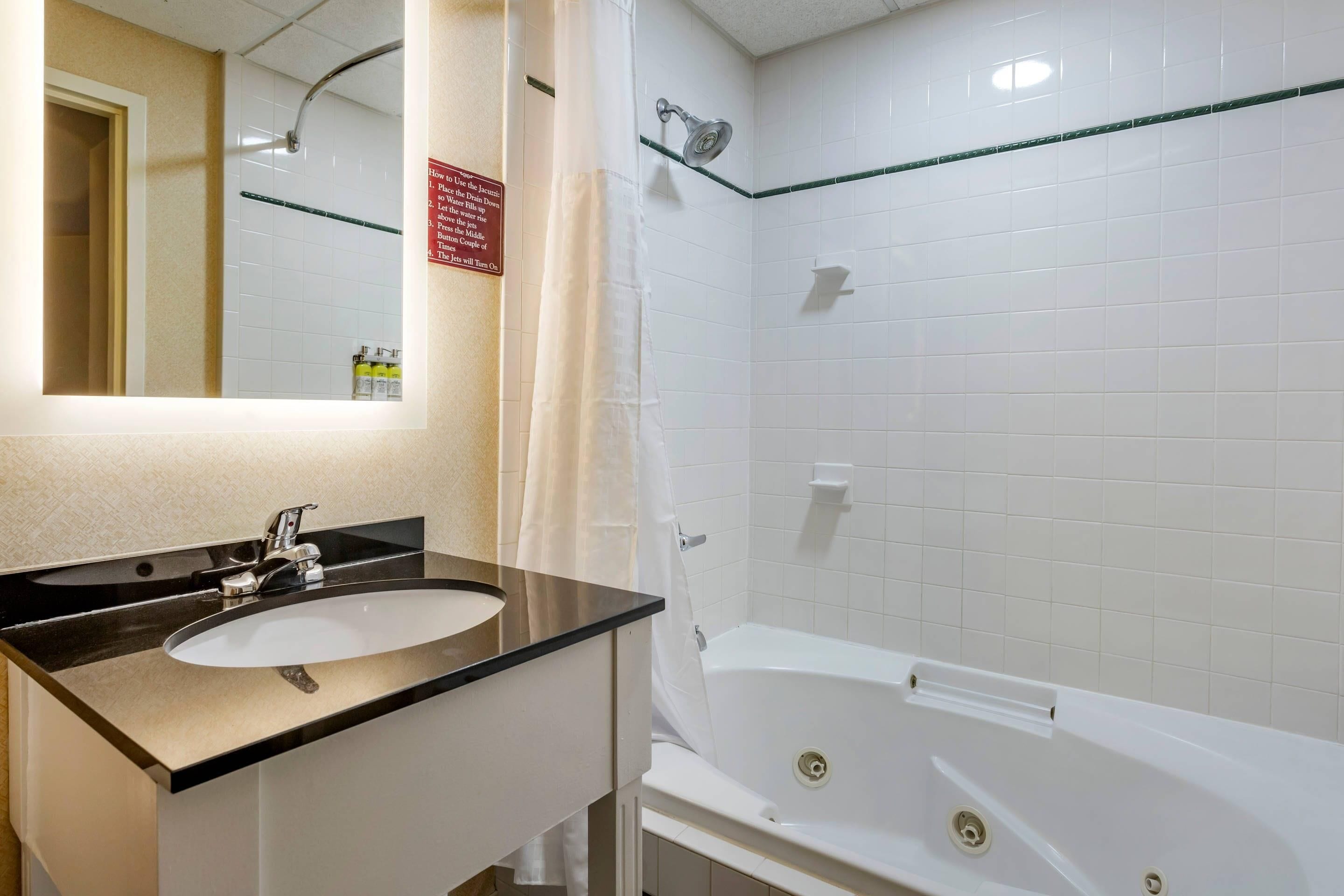 A bathroom with a sink, mirror, shower, and a sign on the wall.