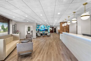 A modern reception area with a wooden reception desk, a seating area with sofas and chairs, and a decorative wall with a geometric pattern.