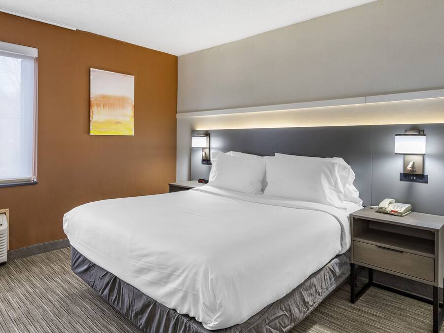 Habitación de hotel con una cama grande, lámparas de noche, una mesita de noche y un teléfono en la pared.