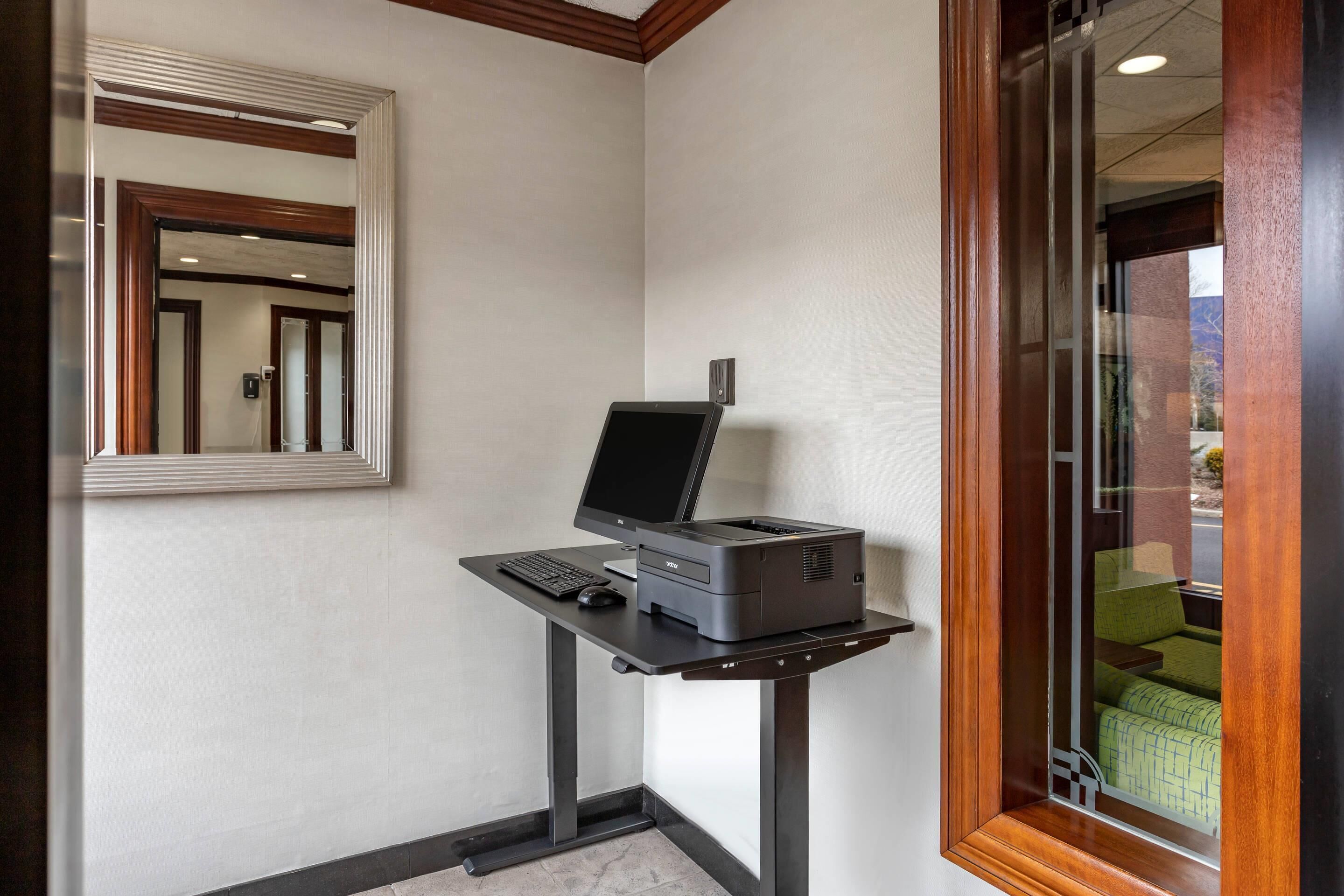 A corner desk with a computer, printer, and keyboard.