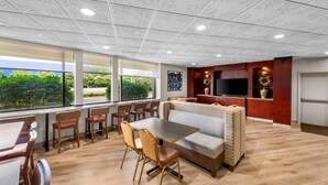 A modern hotel room with a dining area, a sofa, and a TV.