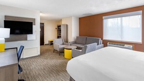 A hotel room with a bed, a TV, a sofa, a small table, and a window.
