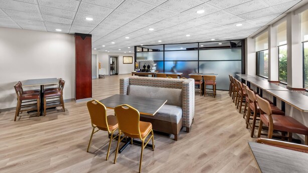 A spacious indoor area with a high ceiling, a sofa, multiple tables, and chairs.
