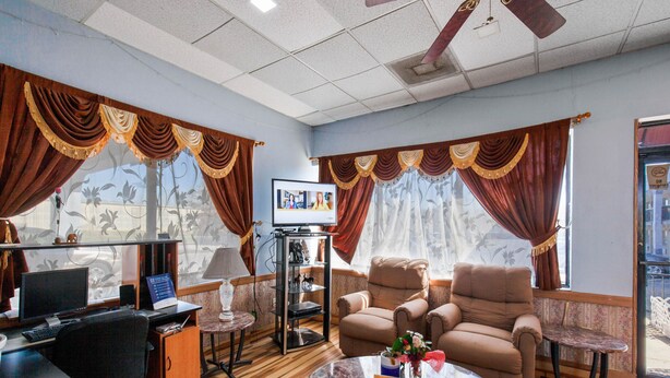 Una sala de estar con sofá, sillones, una mesa de centro, televisor y estantería.
