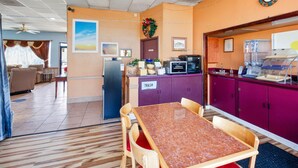 Habitación de hotel con comedor, refrigerador, microondas y un cesto de basura.