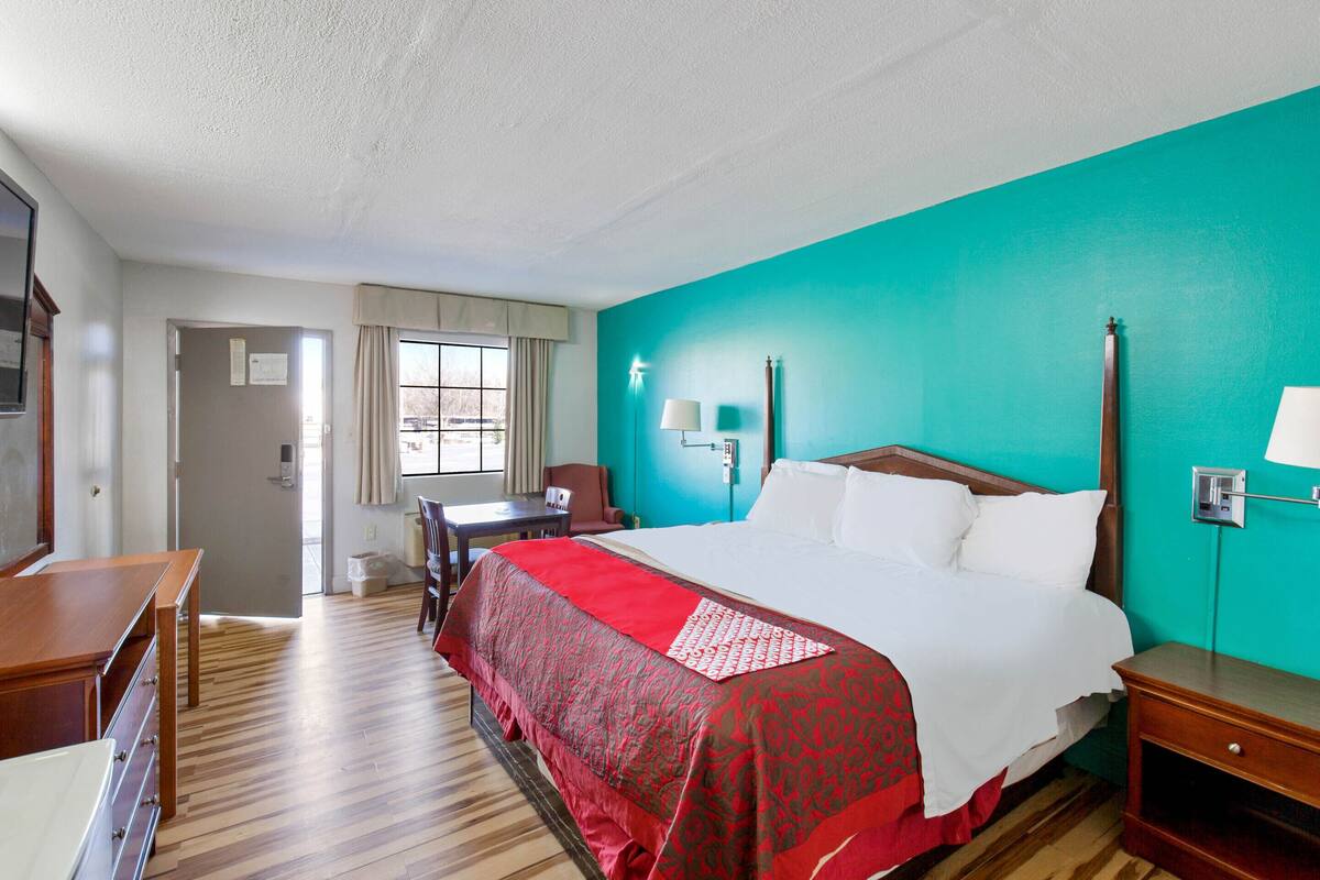 A hotel room with a large bed, a desk, a chair, and a window.