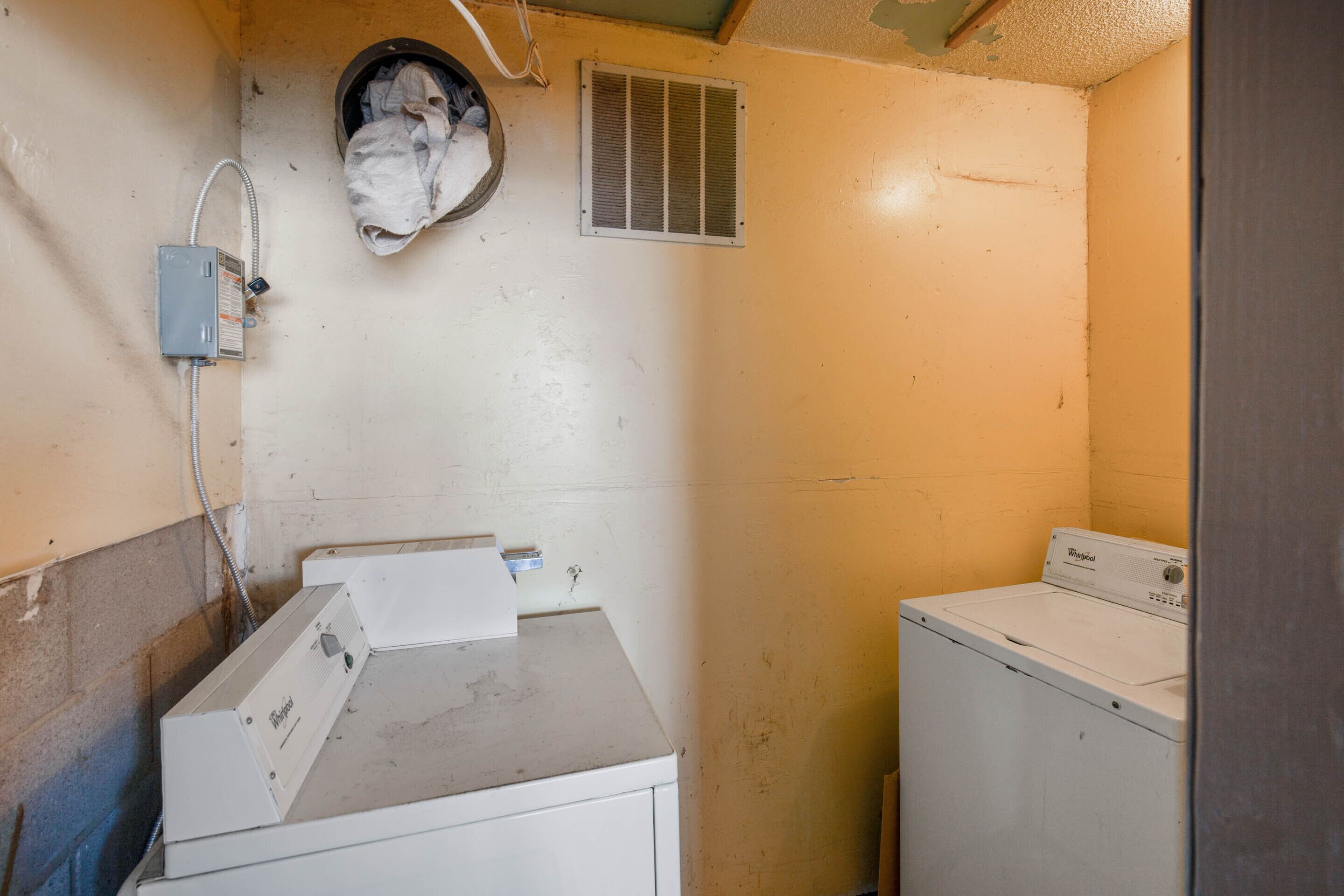 A laundry room with two stacked washers and dryers, a vent, and a power outlet on the wall.