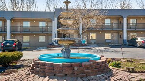 Un motel de varios pisos con un patio central que cuenta con una fuente escalonada y jardines de ladrillo.