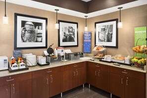A breakfast bar with coffee makers, a waffle maker, and a variety of breakfast items.