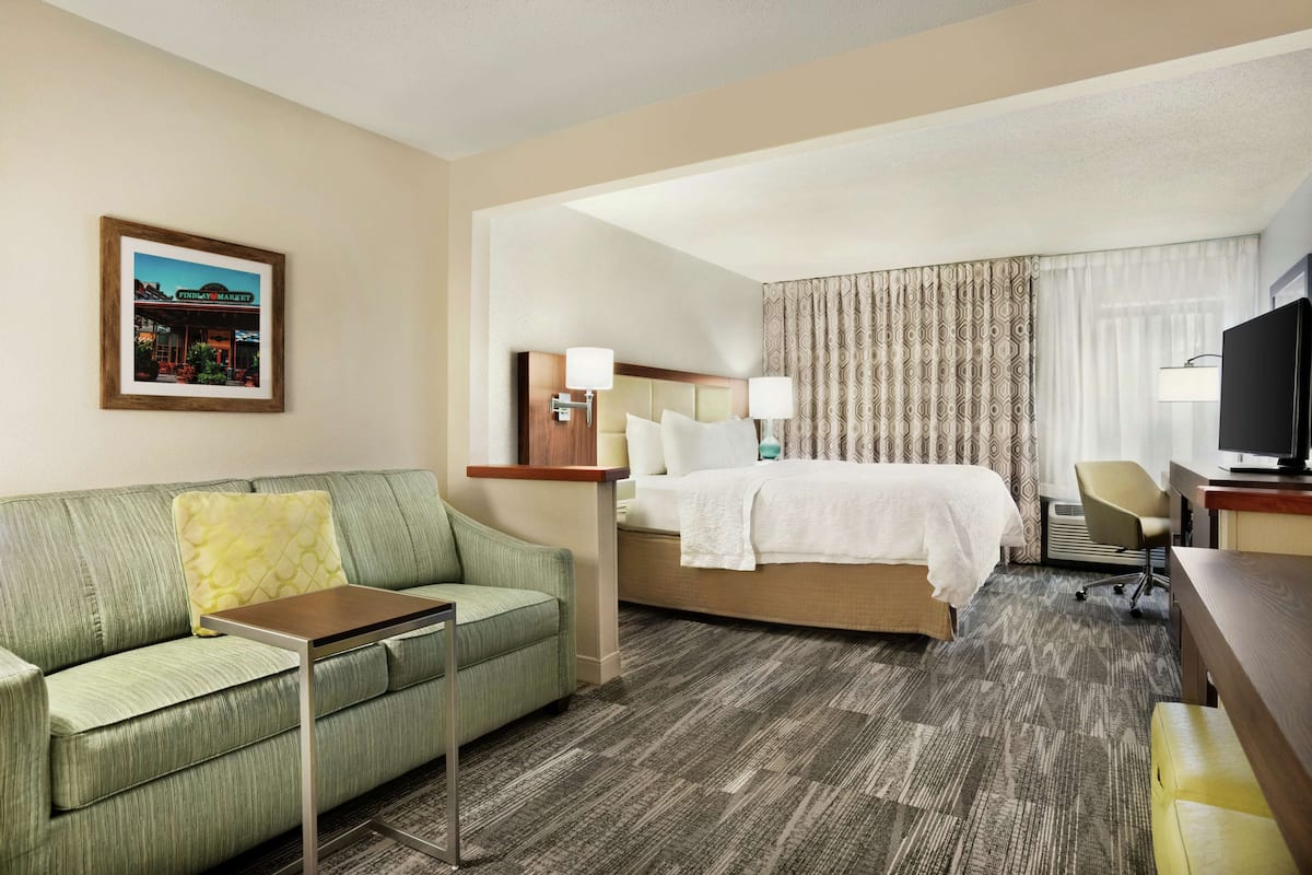 A hotel room with a bed, a sofa, a desk, and a television.