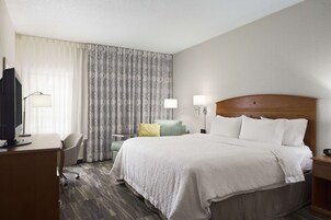 Una habitación de hotel con una cama grande, un escritorio con computadora, una silla y un televisor.