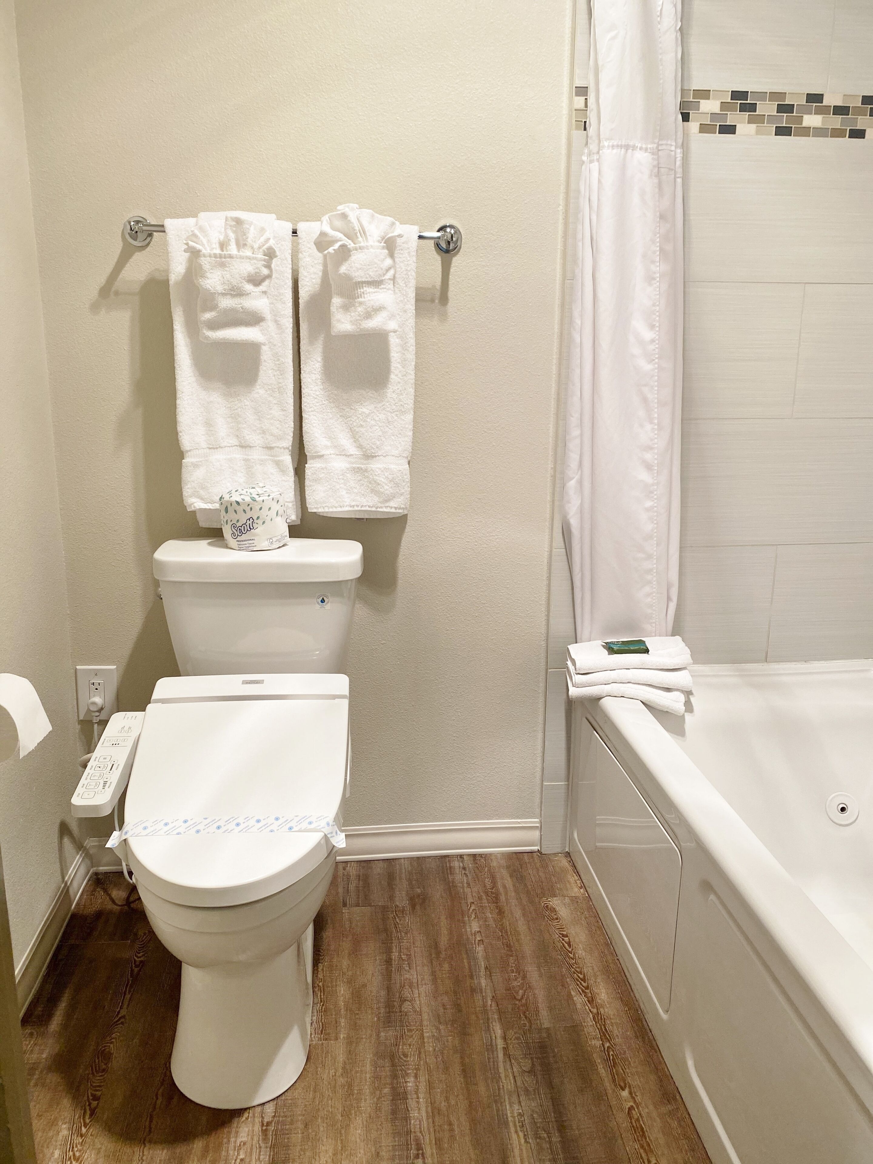 A bathroom with a toilet, a bidet, a bathtub, and a shower curtain.