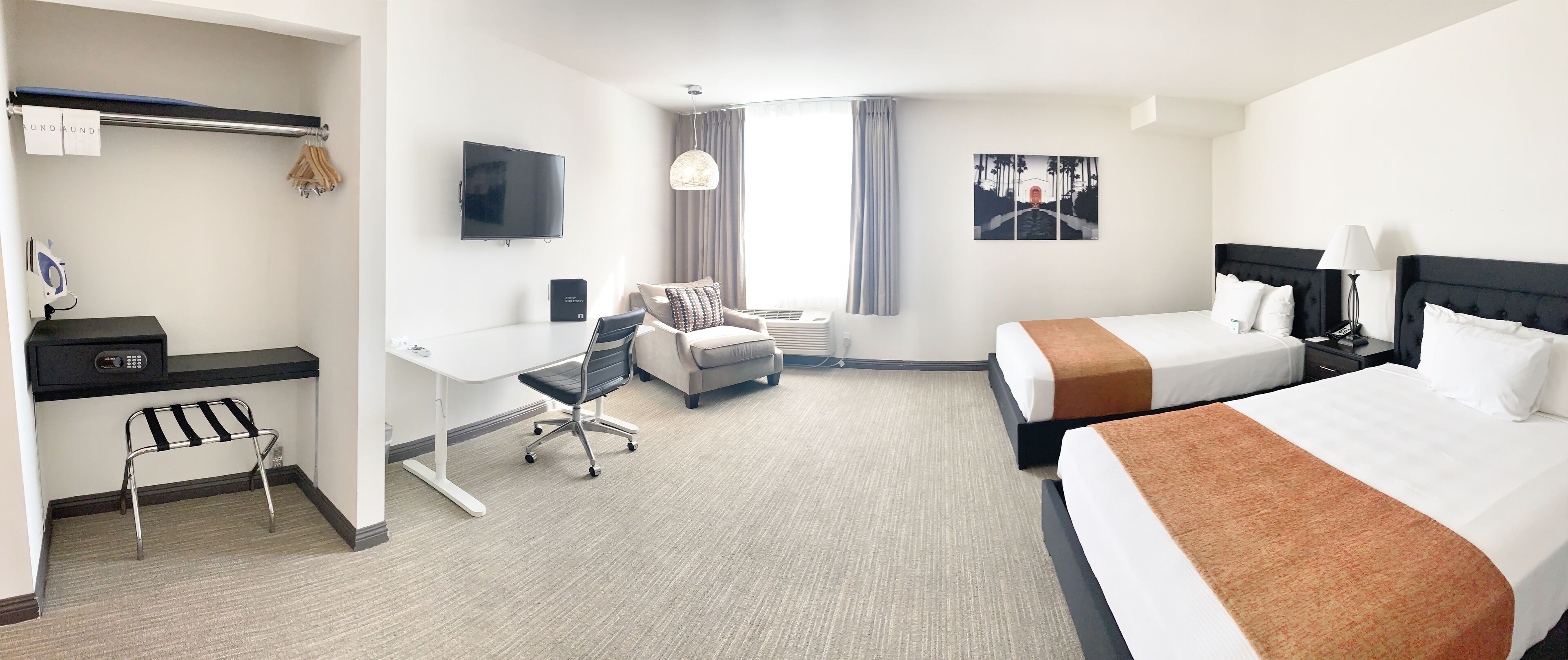 Une chambre d’hôtel avec un lit, un bureau, une chaise, une télévision et une fenêtre avec des rideaux.