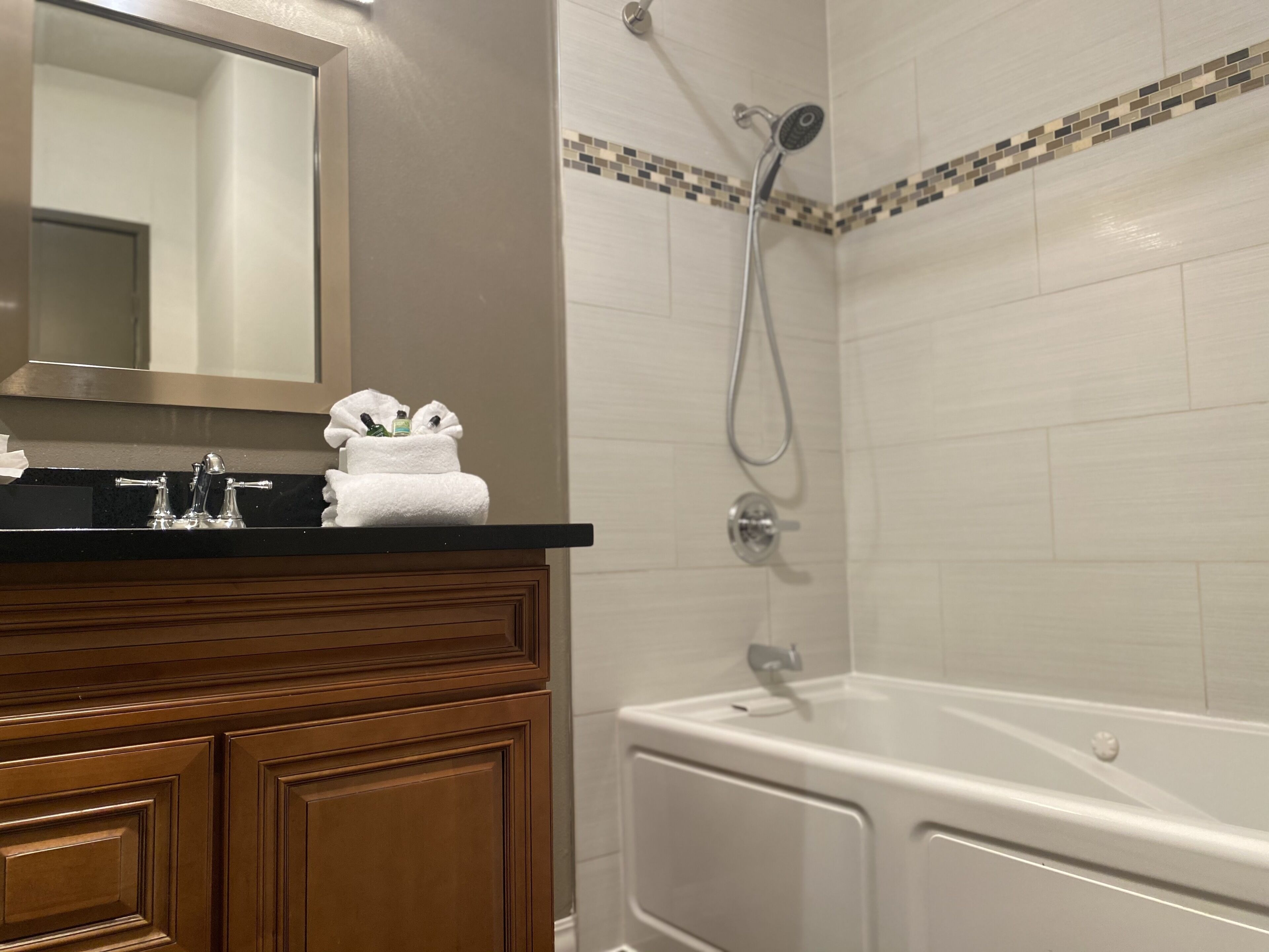 A bathroom with a sink, mirror, and shower.