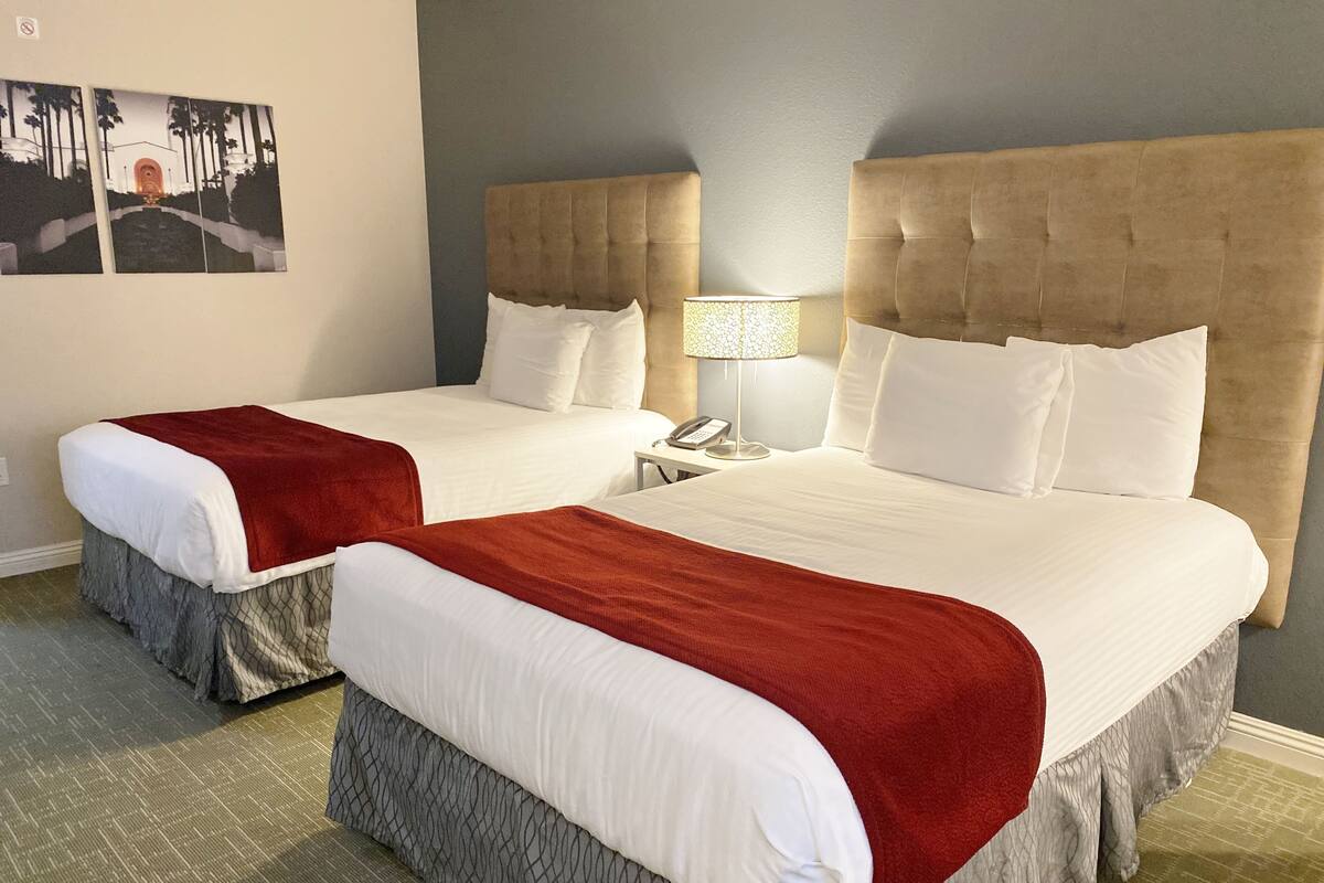 Two double beds with red and white bedding, a telephone, a lamp, and a wall-mounted picture.