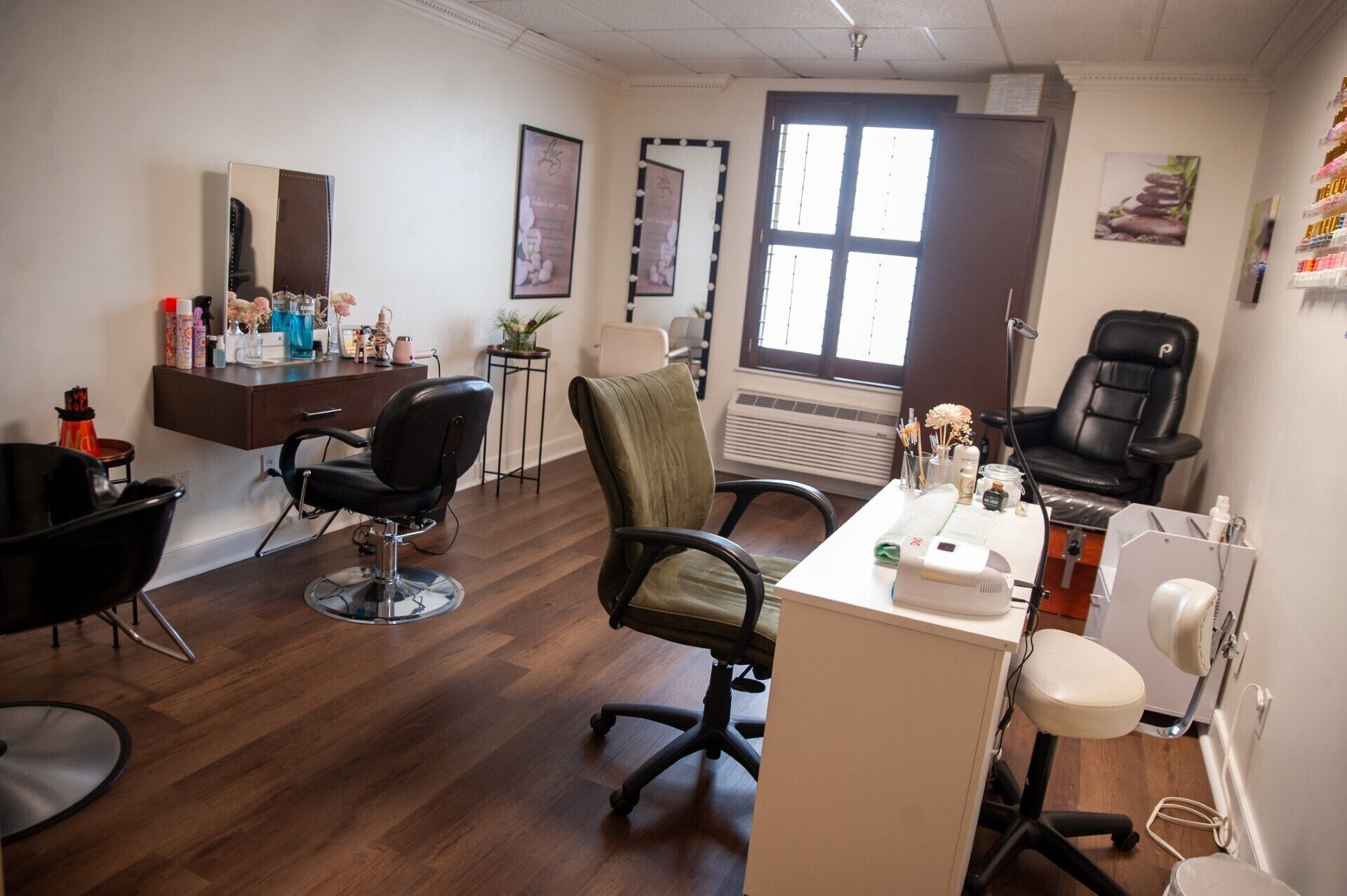 A salon with two black chairs, a white desk, and a mirror.